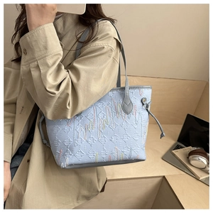 Detail of light blue quilted tote bag with wavy embroidery and drawstring on side