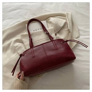 Close-up of deep red leather tote bag with drawstrings on elegant fabric background