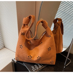 Détail d'un sac cabas en daim marron avec motifs floraux découpés et anse nouée