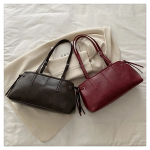 Detail of elegant leather tote bags with drawstring sides in brown and burgundy colors