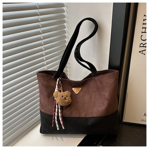 Détail du sac cabas en daim avec plaque triangulaire en métal et breloque ours en peluche