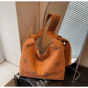 Détail de fleurs découpées au laser sur un sac cabas en daim marron à bandoulière
