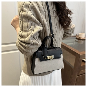 Detail of color-block handbag showing textured fabric and golden lock with shoulder strap