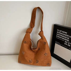 Détail de fleurs découpées au laser et poignée nouée sur le sac cabas en daim caramel