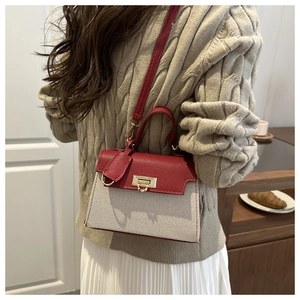 Detail showing the red pebbled leather texture and gold clasp on a beige canvas bag