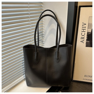 Detail of minimalist black leather tote bag with vertical stitching and matte texture
