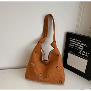 Détail de motif floral découpé au laser sur sac cabas marron mat avec bandoulière nouée