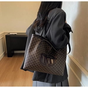 Détail d'un grand sac cabas avec motif M intégral et bandoulière en cuir synthétique