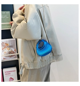 Electric blue crescent acrylic bag with textured stripes shown styled on a model