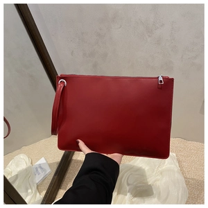 Close-up of red matte leather envelope clutch bag with silver zipper and wrist strap