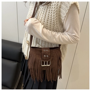 Close-up of brown suede crossbody bag featuring long fringe and a large metal buckle