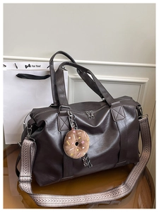 Détail du sac Boston en cuir PU marron foncé avec pendentif en peluche et bandoulière large