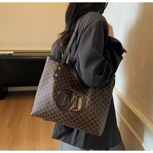 Détail du logo M en cuir embossé sur un sac cabas monogramme marron pour le quotidien