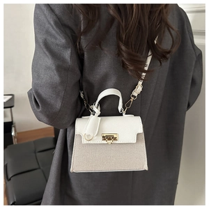Detail of white grain leather and beige fabric拼接 stitching on a stylish handbag