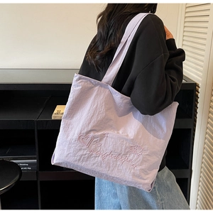 Détail du sac cabas lilas avec broderie en forme de cœur et texture de tissu gaufré