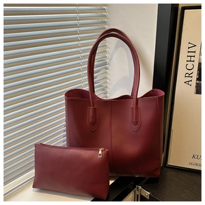 Detail of burgundy leather tote bag with matching zippered pouch in elegant interior setting