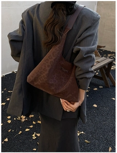 Detail of leopard print faux suede hobo bag featuring a brown leather logo patch