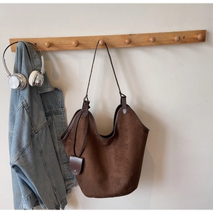 Detail view of large brown suede tote bag with a matching small pouch on a wooden hook