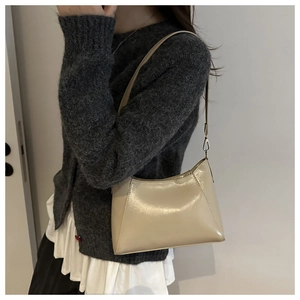 Detail der beigen glänzenden Schultertasche am Modell mit dunklem Pullover Kontrast