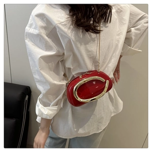 Detailed macro view of the glossy red crossbody bag with a large golden C-shaped hardware