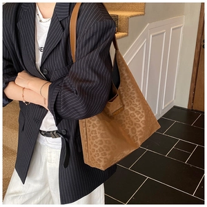 Detail of leopard print tote bag featuring a textured faux suede finish and metal nameplate