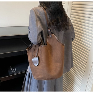Detailed side view of deep brown faux suede tote bag shown on model with leather trim