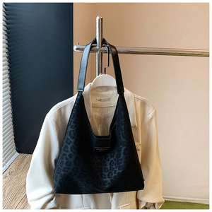 Detail of black suede leopard print tote with premium leather logo tag and sturdy straps