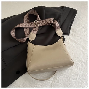 Detail der beigen Hobo-Tasche mit gemustertem Webriemen und goldener Schließe