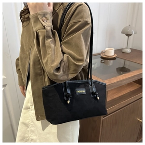 Detail of black suede tote bag with yellow FASHION patch and long shoulder straps