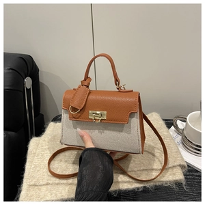 Detail of the chic mini handbag featuring brown lychee leather and beige woven fabric textures