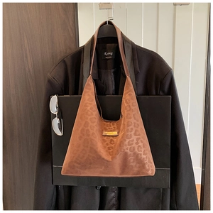 Detail of leopard print faux suede tote bag with wide shoulder strap and leather patch