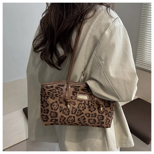 Detail of leopard print tote bag with brown leather shoulder strap and fashion label
