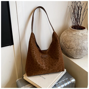 Brown leopard print suede hobo bag styled on a travel suitcase for fashion commute