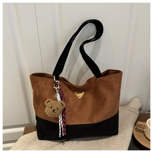 Detalle del bolso tote bicolor en ante marrón con un encantador colgante de oso de peluche