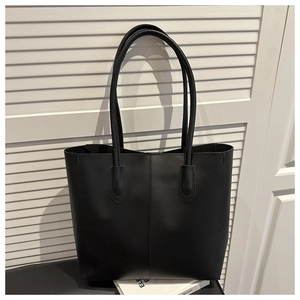 Close-up of a minimalist black leather tote bag with elegant stitching and slim shoulder straps