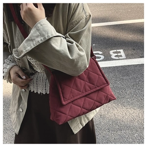 Detail of burgundy quilted crossbody bag with soft diamond stitching and long strap