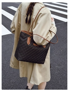 Quilted black tote bag with brown leather straps shown in a street style fashion setting