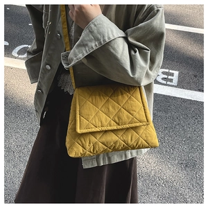 Close-up of yellow quilted nylon crossbody bag with rhombic pattern worn by model