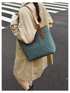 Detail of dark green quilted tote bag with brown straps styled with a trench coat