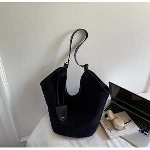 Detail of minimalist black tote bag with long leather strap and teardrop charm accessory