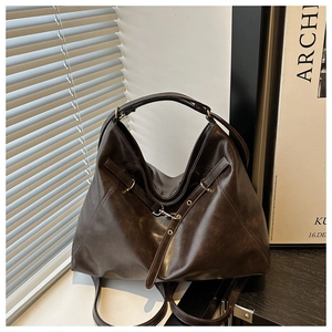 Detail of dark brown leather tote bag with metallic buckle against soft window light