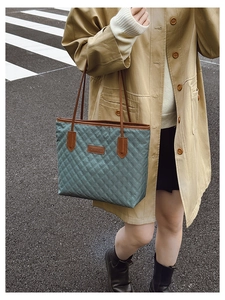 Detailed shot of sage green quilted tote bag featuring brown leather trim and fashion tag