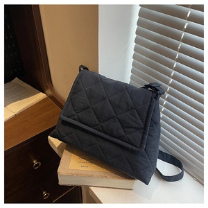 Detailed view of black quilted nylon crossbody bag with diamond stitching and adjustable strap