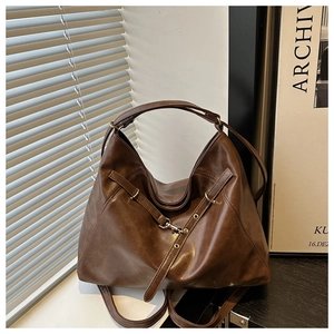 Detail of vintage brown tote bag with metal buckles and matte leather texture in side light