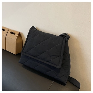 Detail of black quilted shoulder bag with fine stitching and adjustable textile strap