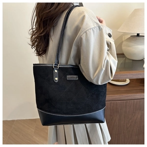 Detail of the black quilted tote bag featuring mixed textures and a FASHION metal plate