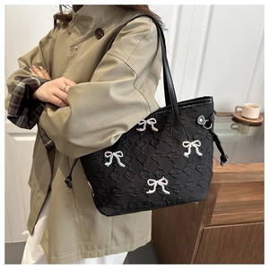 Close-up of quilted tote bag featuring embroidered bows and delicate sequin details