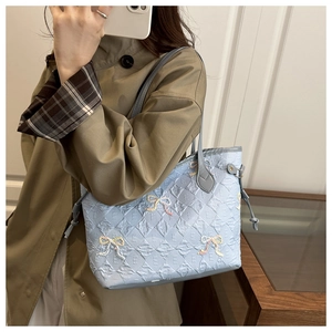 Detail of embroidered bow and quilted E pattern on light blue large tote shoulder bag