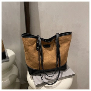 Close-up of brown suede tote bag with quilted diamond pattern and black leather contrast
