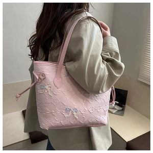 Detail of pink tote bag with F-pattern embossing and colorful butterfly embroidery